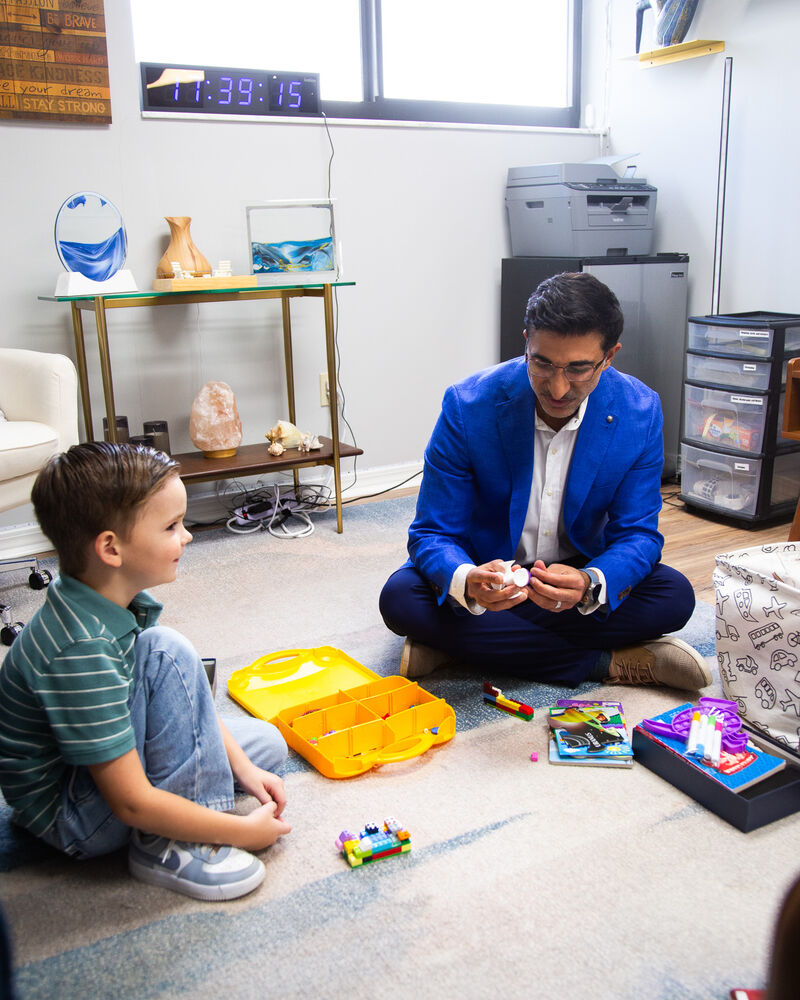 Dr. Loungani sitting on the floor with a young boy and his toys