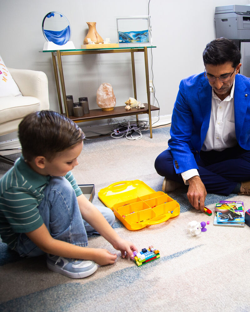 Dr. Loungani on the floor with a young boy and a box of toys