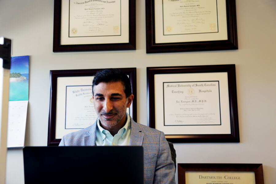 Dr. Raj Loungani at his desk in front of his diplomas